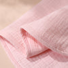 Pink baby burp cloths folded and stacked, showing soft fabric texture.