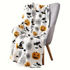 A gray armchair is draped with a white flannel throw blanket featuring an all-over spooky Halloween print of bats, spiders, a