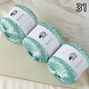 Three skeins of turquoise glitter yarn labeled MuYuan Frost Words displayed on a light surface.