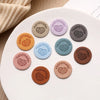 A collection of round, handmade PU leather labels in various earthy and pastel tones arranged on a white surface.
