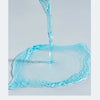 A hand pours clear blue liquid from a glass onto a surface, creating ripples.