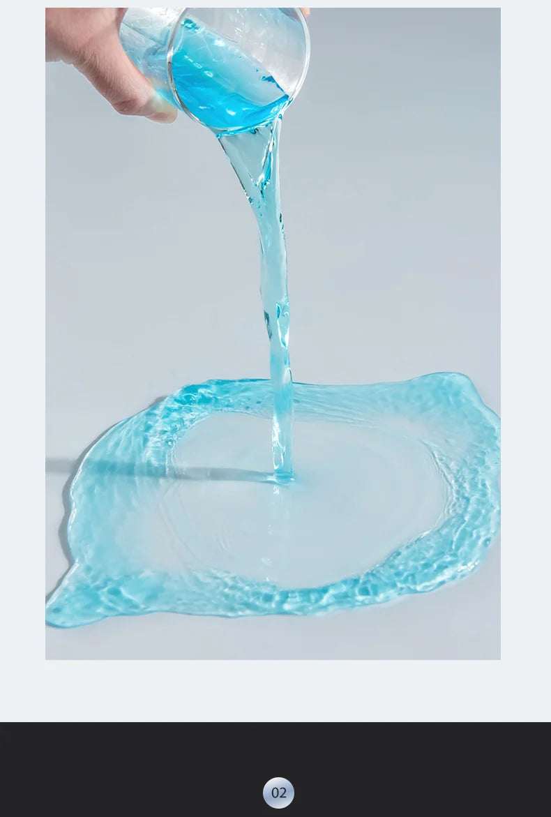 A hand pours clear blue liquid from a glass onto a surface, creating ripples.