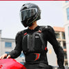 A person wearing a black motocross armor jacket with chest and back protection is shown next to a red motorcycle.