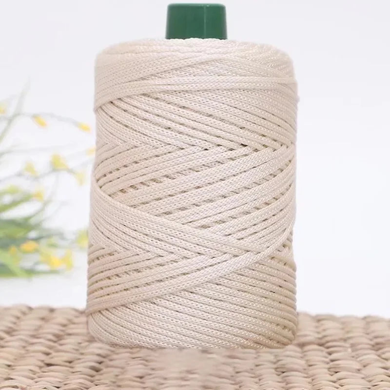 Ein Spul und 3mm Tauwerk-Kordel aus Beige mit grünem Kopf liegt auf einer gewebten Matte.