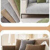 A close-up of a sofa covered in various textured pillows and a solid brown sofa cover.
