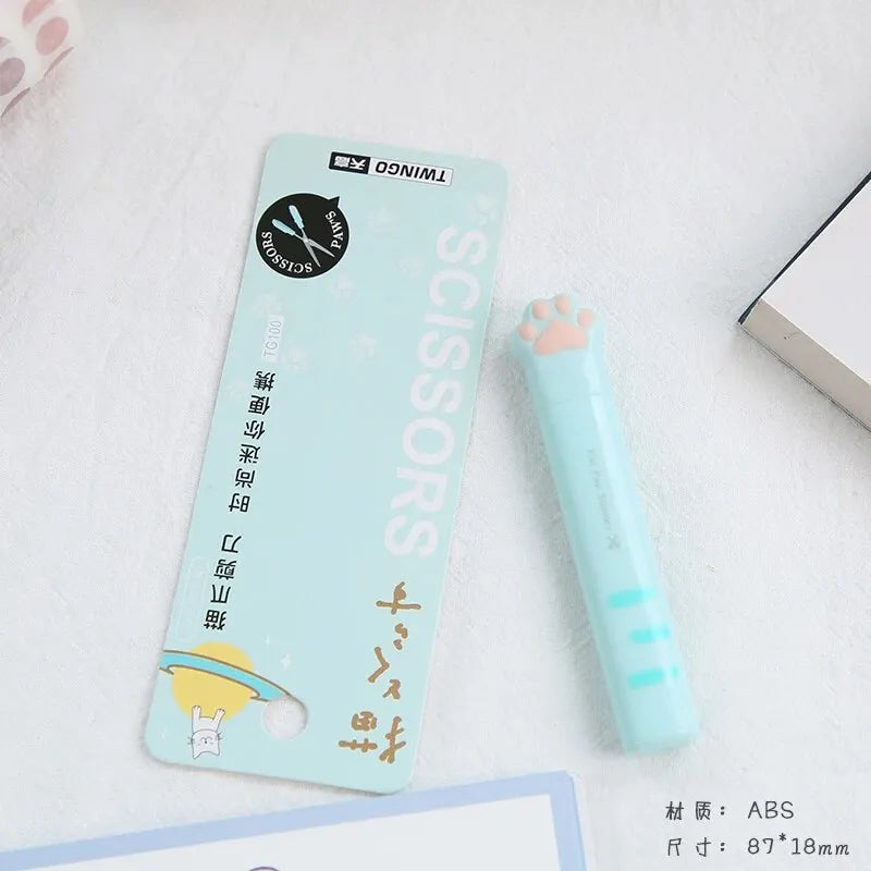 A light blue portable scissors product with a cat paw design is shown next to its packaging.