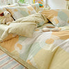 A beige and sage green duvet cover set with patterned pillows and a stuffed animal on a bed.