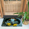 A black door mat featuring a distressed horror clown face with yellow gloves.