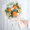 Bouquet aus handgefertigten Häkel-Sonnenblumen und weißen Blumen in rosa Papier mit grünem Blattlabel