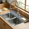 A stainless steel faucet mat is placed in a kitchen sink, with water flowing from the faucet.