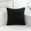 A black knitted pillowcase with a ribbed texture resting on a white surface.