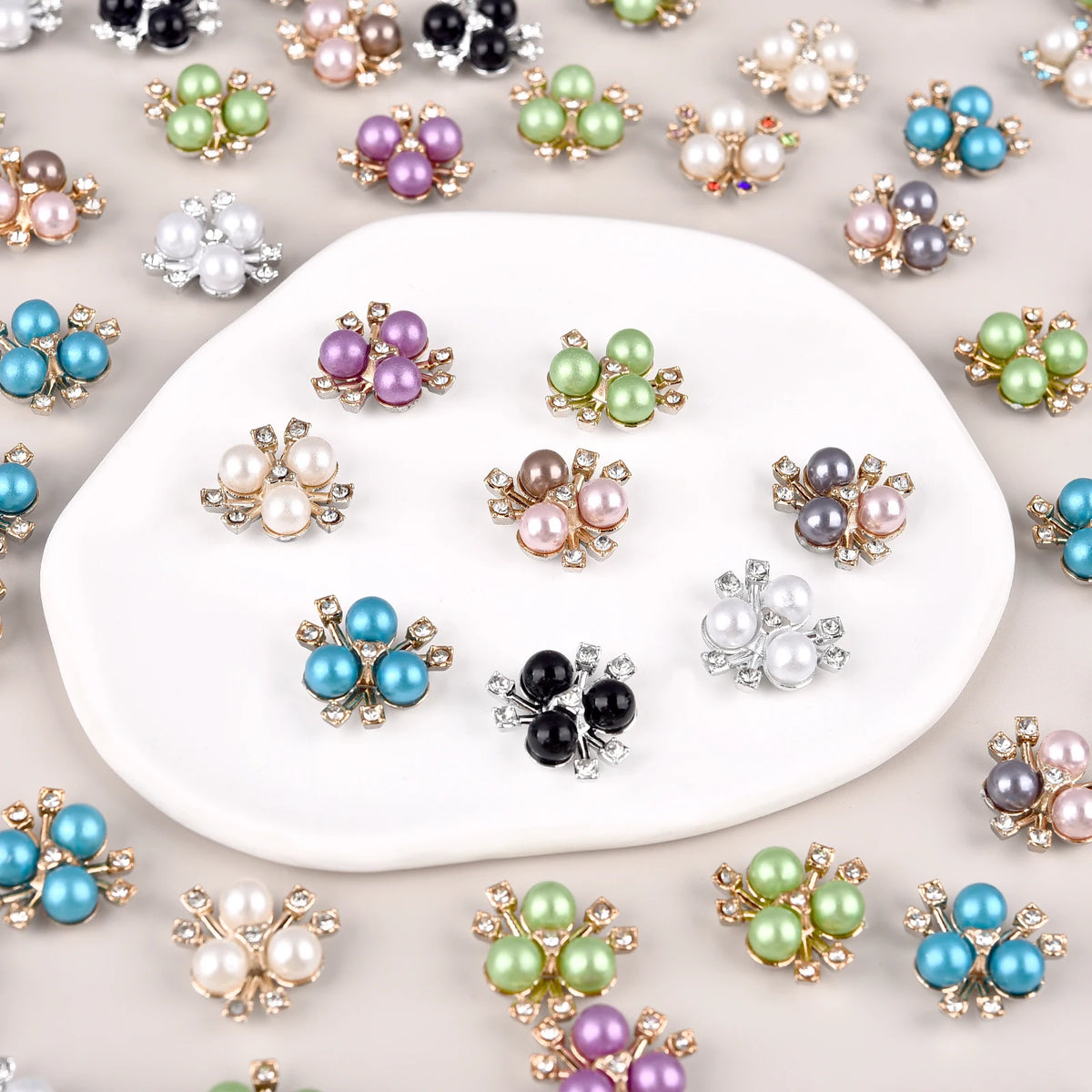 A collection of pearlized resin flower beads in various shades of green, purple, and blue scattered on a white surface.