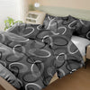 A set of three geometric print duvet covers and pillowcases in shades of gray and white on a bed.