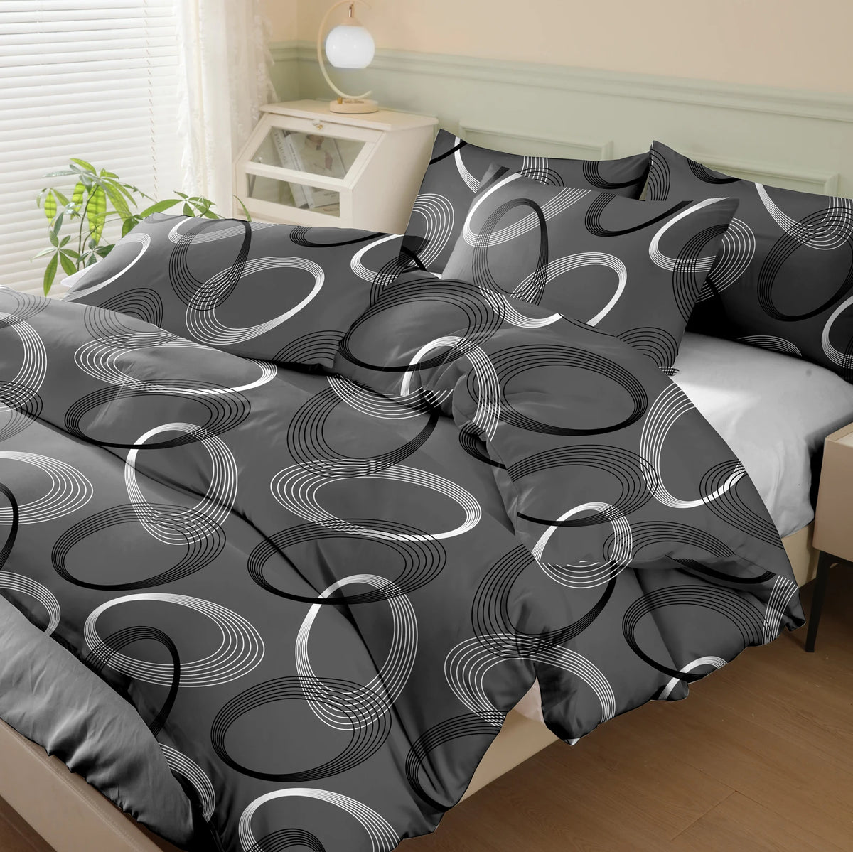 A set of three geometric print duvet covers and pillowcases in shades of gray and white on a bed.