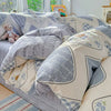 A set of light gray and white patterned cotton duvet covers and pillow shams displayed on a bed.