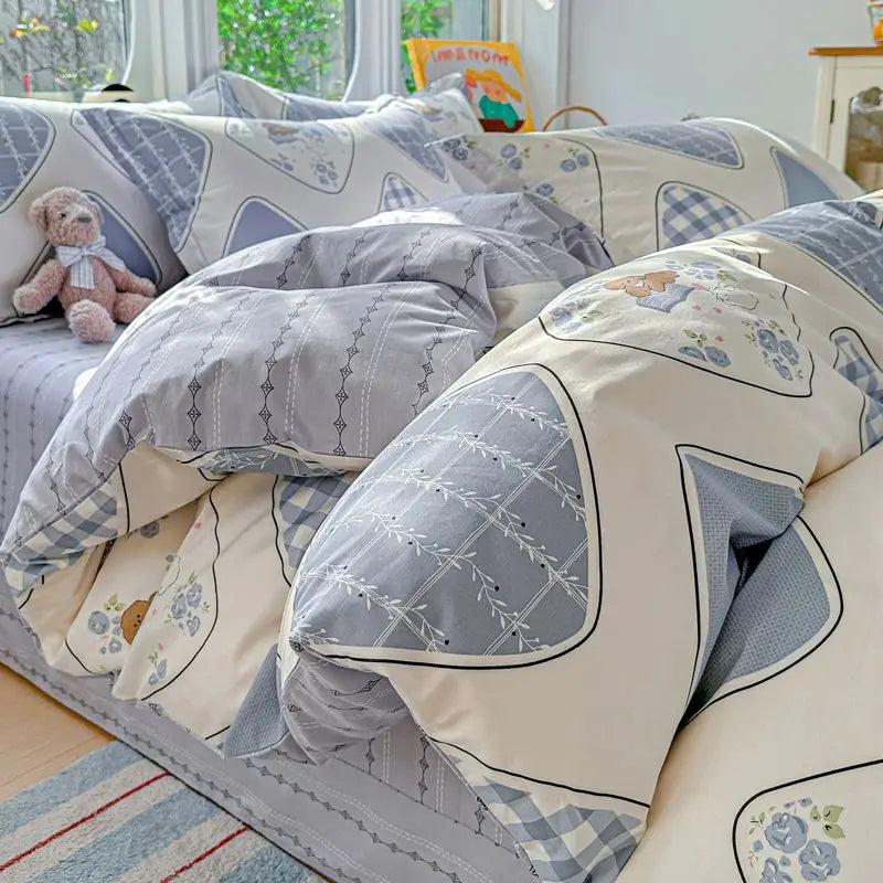 A set of light gray and white patterned cotton duvet covers and pillow shams displayed on a bed.