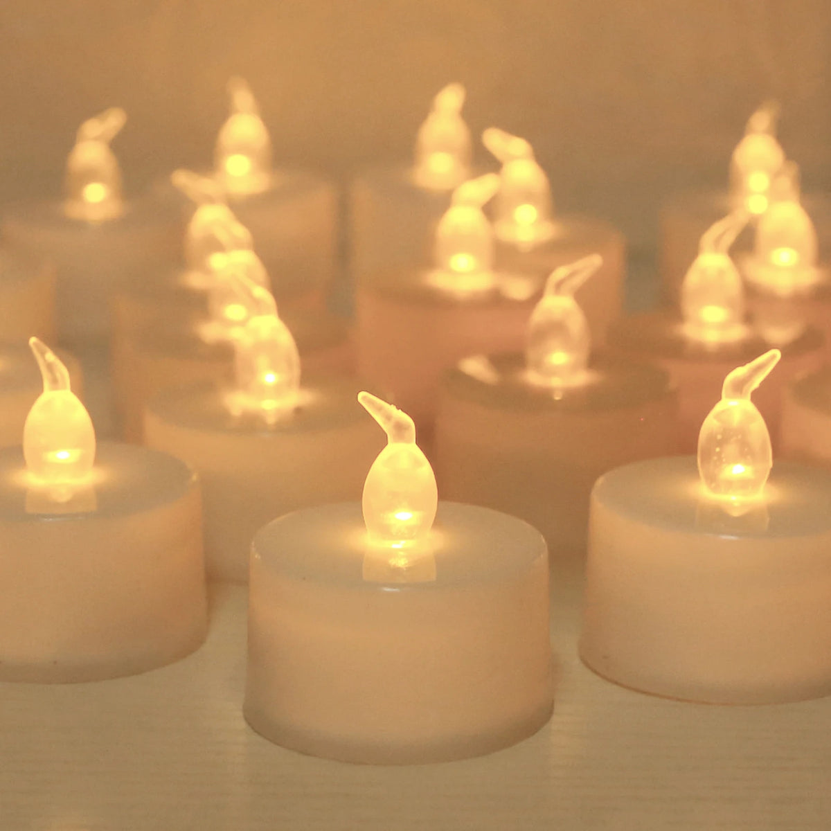 A close-up of a set of glowing LED tea lights with flickering flames arranged on a surface.