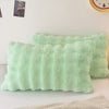 A light mint green faux fur pillow is displayed on a white surface.