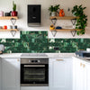 A kitchen backsplash featuring green marble self-adhesive tiles with gold veining and wooden shelving.