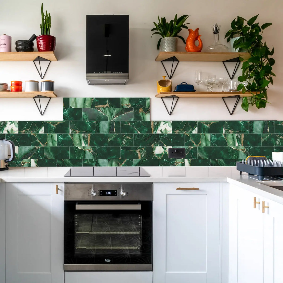 A kitchen backsplash featuring green marble self-adhesive tiles with gold veining and wooden shelving.
