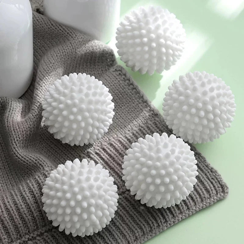 A collection of white reusable laundry balls resting on a gray knitted fabric.