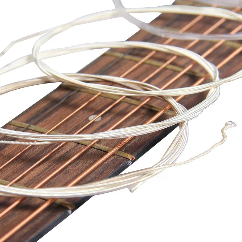 A set of thin, light-colored classical guitar strings coiled on a wooden fretboard with a winding tool.