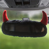A black devil horn rearview mirror cover with red accents is shown against a blurred green background.