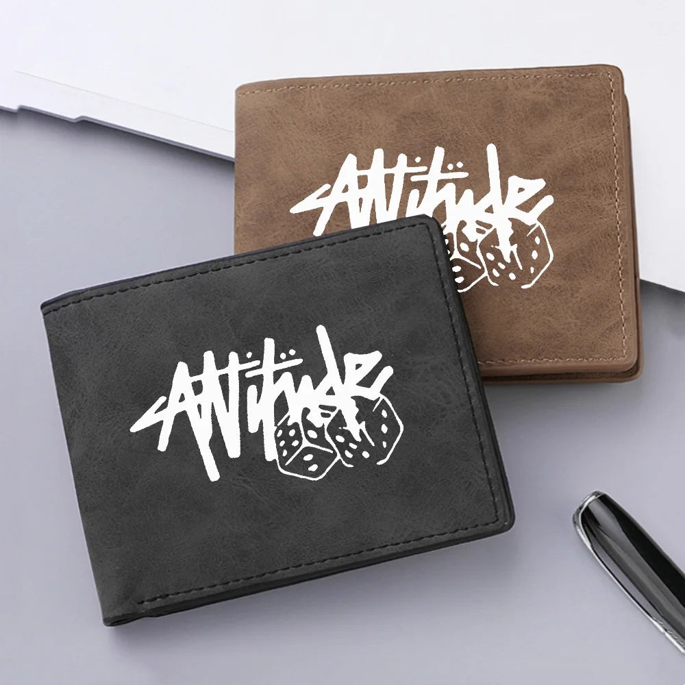 A dark gray leather wallet with white stylized text and dice design is shown next to a brown leather wallet.
