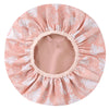 A large pink and white floral patterned satin-lined waterproof shower cap for hair protection.