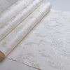 Rolls of embossed damask wallpaper featuring a textured floral design on white fabric.