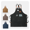 A black professional chef apron with cross-back straps and tool pockets shown alongside its natural leather straps.