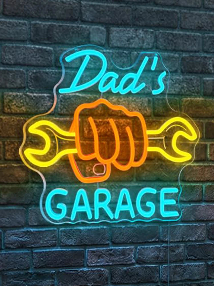 Blue and orange neon sign on a brick wall spelling out Dad's Garage