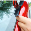 A hand is applying a black rubber seal strip to the edge of a red car window frame.