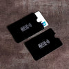 A black RFID blocking card sleeve is placed on a brown textured surface.