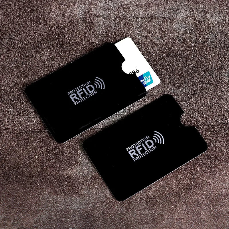 A black RFID blocking card sleeve is placed on a brown textured surface.