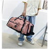 A person is holding a pink tactical nylon backpack with black accents against a white wall.