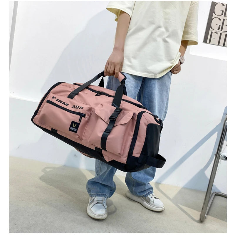 A person is holding a pink tactical nylon backpack with black accents against a white wall.