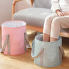A light pink and mint green foldable insulated foot soak tub is shown next to a person sitting on a chair.