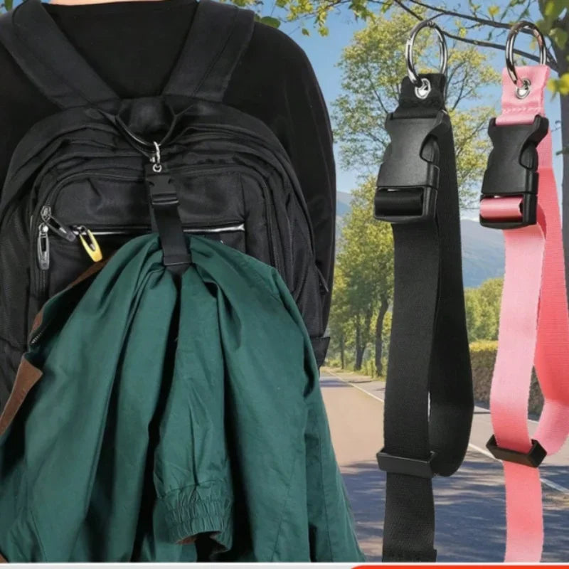 A dark green fabric item is shown hanging from an adjustable black and pink luggage strap.
