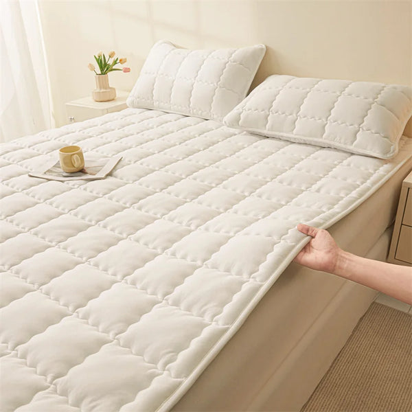 Gepitztes weißes Matratzen-Topper mit rutschfester Unterlage und passender Kissen auf einem Bett.