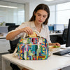 A woman holds an insulated picnic lunch bag with a cross-body strap on a white desk.
