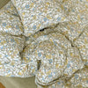 A close-up of a soft printed duvet cover set featuring a white background with yellow and blue floral patterns.