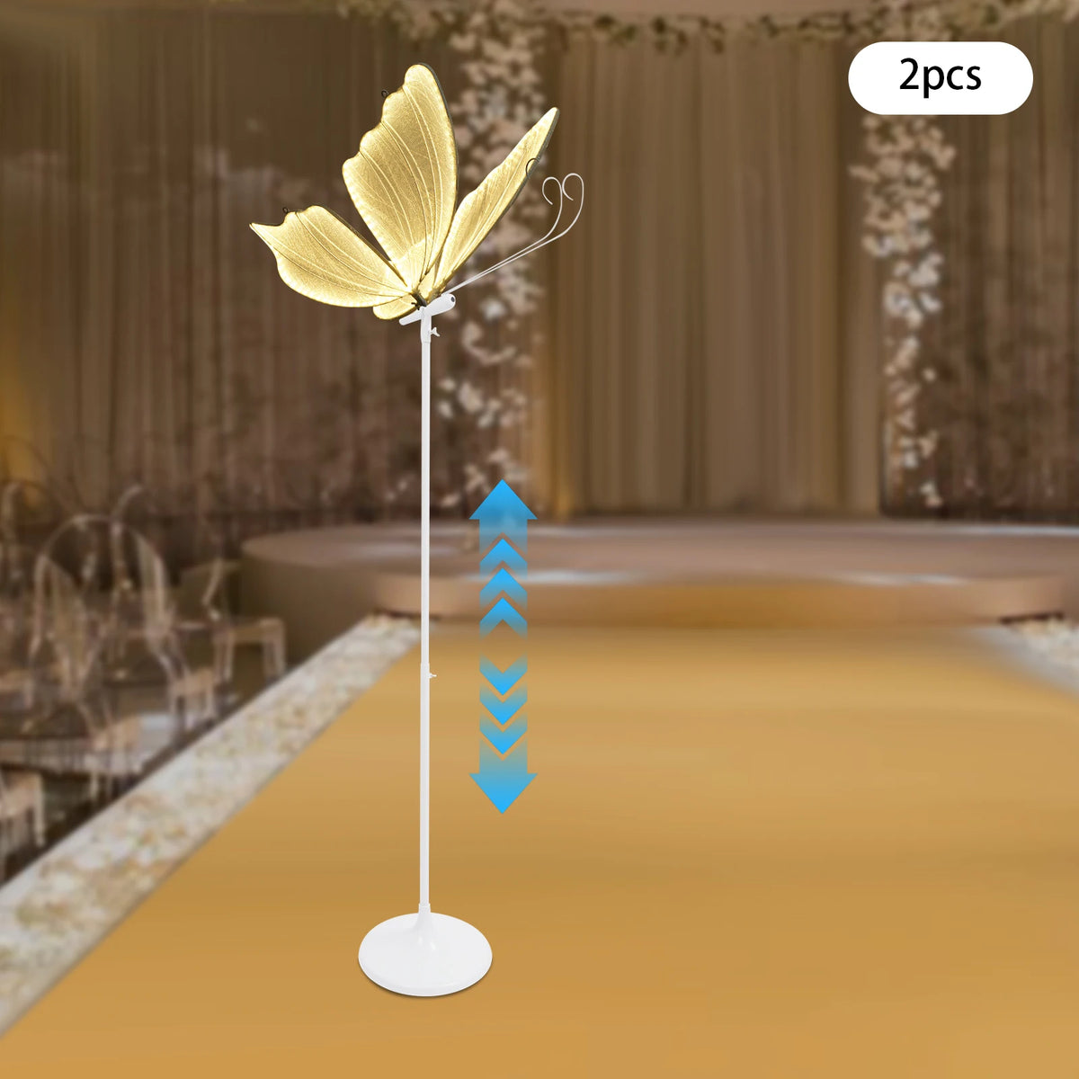 Ein Set aus zwei goldenen Schmetterlingsfußlampen auf einem weißen Ständer vor unscharfem Hintergrund.