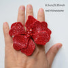 A hand holds a red rhinestone flower sew-on patch, measuring 8.5cm/3.35inch.