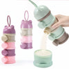 A hand is holding a stack of three bear-shaped baby food storage containers in various shades of pink and green, with some po