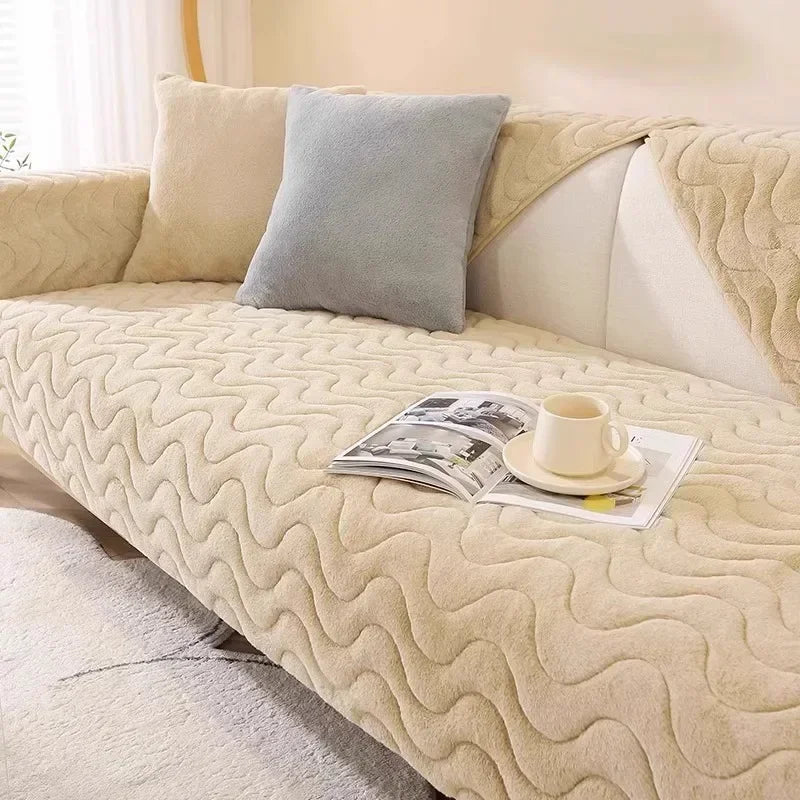 A beige plush sofa cushion mat with a quilted texture and a gray accent pillow on a light-colored sofa.