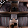 Interior view of a car with dark brown quilted leather floor mats and a center console.