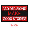 Black embroidered iron-on letter patch with red text that reads BAD DECISIONS MAKE GOOD STORIES