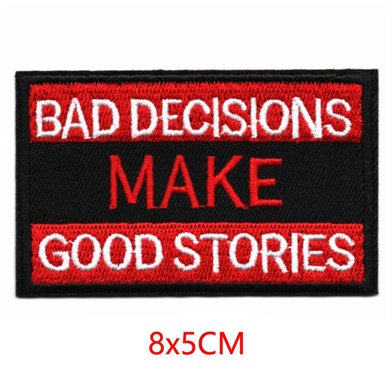 Black embroidered iron-on letter patch with red text that reads BAD DECISIONS MAKE GOOD STORIES