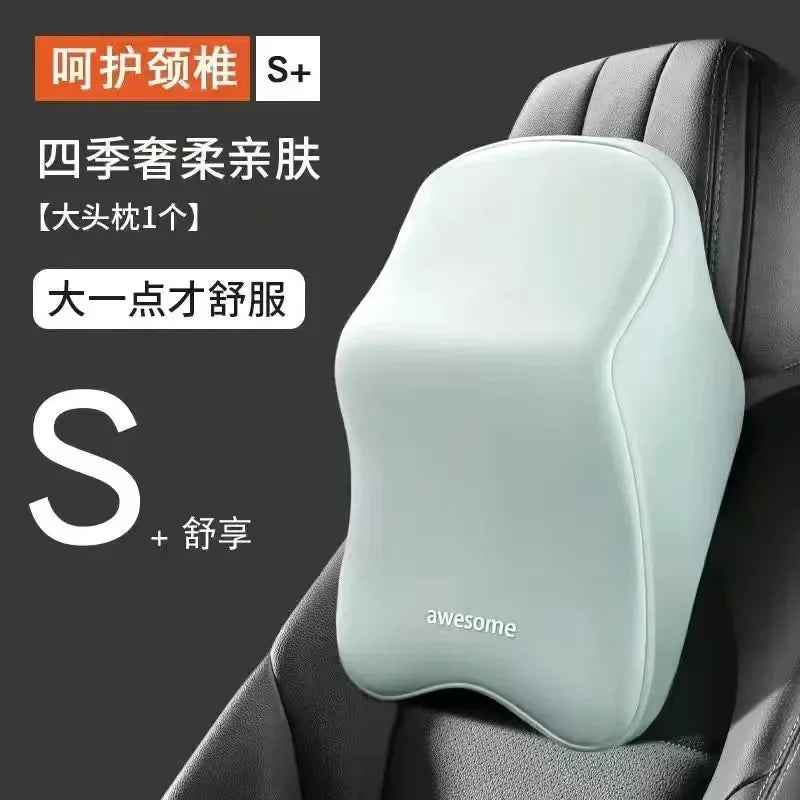 A light gray memory foam car headrest and lumbar support pillow placed on a dark gray seat cushion.